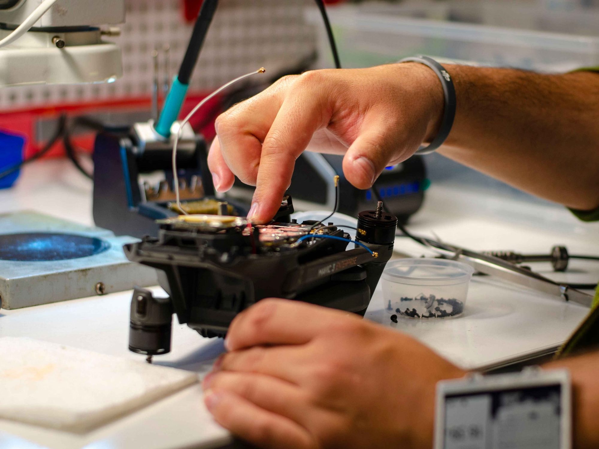 Hände arbeiten mit Lötkolben an der Elektronik einer Drohne